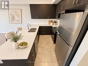 Haldimand townhouse for rent - A modern kitchen with a stainless steel refrigerator and black cabinets.
