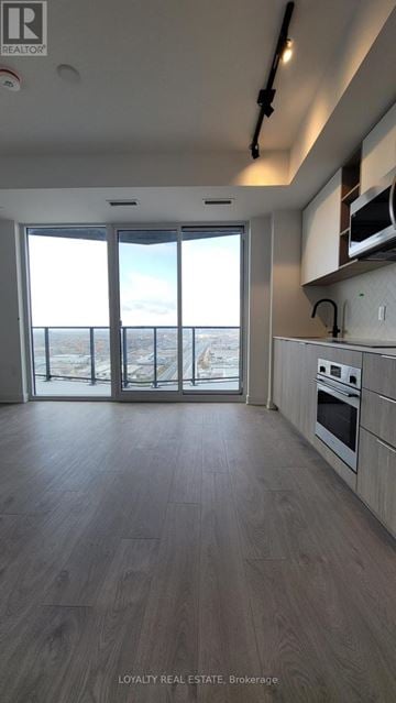 Toronto (Islington-City Centre West) condo for rent - A kitchen with a view of the city through the sliding glass doors.