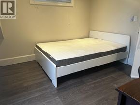 Vancouver apartment for rent - A white bed with a black mattress is in a room with a wooden floor.