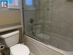 Vancouver apartment for rent - A white toilet sits next to a glass shower door.