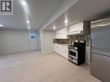 Maple Ridge apartment for rent - A modern kitchen with stainless steel appliances and a stone backsplash.