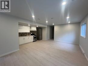 Maple Ridge apartment for rent - A spacious room with a kitchen area and a door leading to another room.