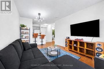 Toronto (Lansing-Westgate) condo for rent - A living room with a black sofa and a flat screen TV mounted on the wall.