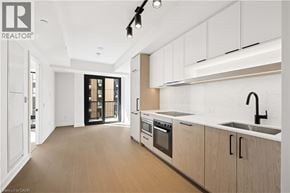 Toronto condo for rent - A modern kitchen with white cabinets and a black faucet.