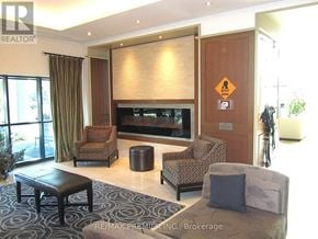 Brampton (Downtown Brampton) condo for rent - A living room with a brown sofa, a black coffee table, and a television.