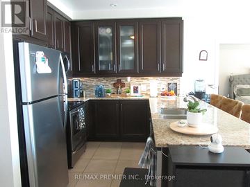 Brampton (Downtown Brampton) condo for rent - A kitchen with a refrigerator and a stove top oven.