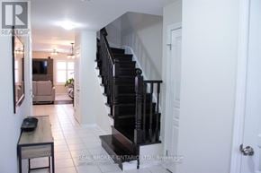 Hamilton (Stoney Creek) townhouse for rent - A hallway with a staircase and a table with a plant on it.