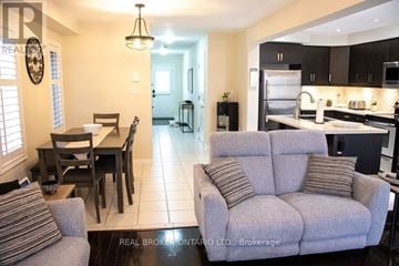 Hamilton (Stoney Creek) townhouse for rent - A living room with a grey couch and a dining table with chairs.