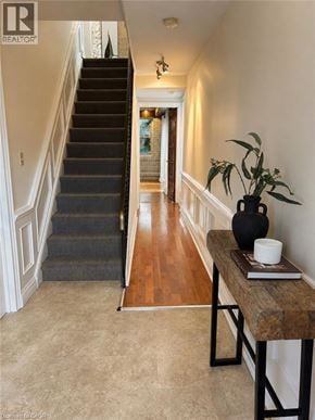 Hamilton apartment for rent - A hallway with a staircase and a table with a vase and a book on it.