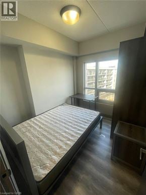 Waterloo condo for rent - A bedroom with a large bed and a window overlooking a balcony.
