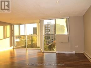 London South (South O) condo for rent - A room with wooden floors and a large window overlooking a cityscape.