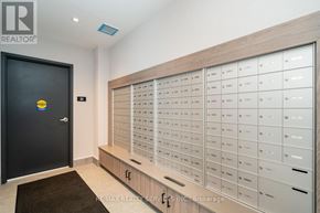 Barrie (Little Lake) condo for rent - A black door with a yellow sign on it and a wall of mailboxes.