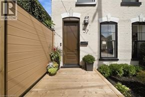 Brantford apartment for rent - A brown wooden door is on the left side of a white building with a black window.
