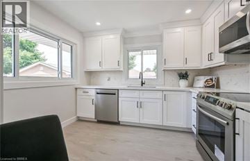 Brantford apartment for rent - A kitchen with white cabinets and a black chair.