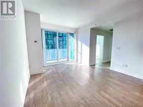 Toronto (Lansing-Westgate) condo for rent - A room with wooden flooring and a large window with a view of the city.