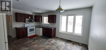 Pickering (Rosebank) apartment for rent - A kitchen with brown cabinets and a white stove top oven.
