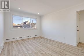Ottawa condo for rent - A room with wooden flooring and a large window showing a view of buildings outside.