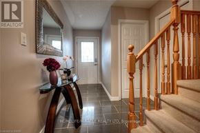 Kitchener apartment for rent - A hallway with a wooden staircase and a mirror on the wall.