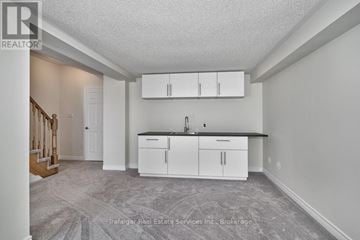Oakville (Wm Westmount) townhouse for rent - A real estate listing image of a kitchen with white cabinets and a black countertop.