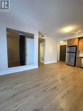 Toronto (Waterfront Communities) condo for rent - A spacious room with wooden flooring and a large mirror on the wall.