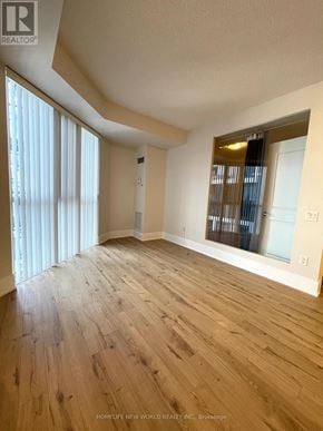 Toronto (Waterfront Communities) condo for rent - A spacious room with wooden flooring and a large window with blinds.