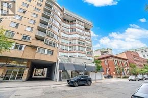 Toronto (Church-Yonge Corridor) condo for rent - A black car is parked in front of a building with the sign "Royal LePage Meadowtowne Realty Brokerage.".