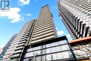 Toronto (Church-Yonge Corridor) condo for rent - A tall building with a glass facade stands in front of two other buildings.
