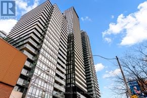 Toronto (Church-Yonge Corridor) condo for rent - A tall building with a glass facade stands under a blue sky.