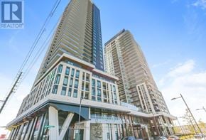 Vaughan (Vaughan Corporate Centre) condo for rent - A modern multi-story building with a glass facade stands tall against a clear sky.
