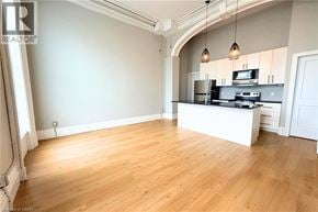 Hamilton apartment for rent - A spacious room with wooden flooring and a kitchen area with a stove and cabinets.