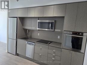 Toronto (Waterfront Communities) condo for rent - A modern kitchen with a stainless steel refrigerator, microwave, and oven.