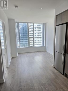 Toronto (Waterfront Communities) condo for rent - A spacious kitchen with a refrigerator and a view of a high-rise building outside the window.