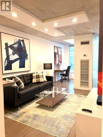 Toronto (Waterfront Communities) condo for rent - A modern living room with a black couch and a large abstract painting on the wall.