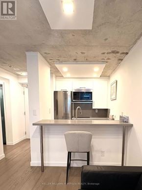Toronto (Waterfront Communities) condo for rent - A modern kitchen with a stainless steel island and a single bar stool.