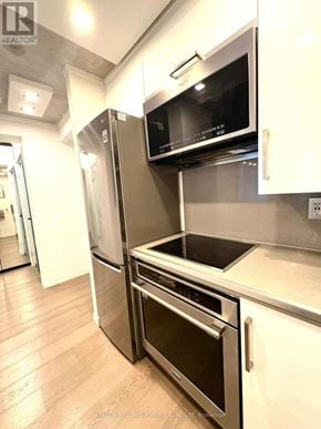Toronto (Waterfront Communities) condo for rent - A modern kitchen with stainless steel appliances and wooden floors.