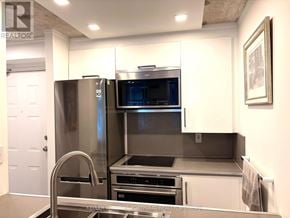 Toronto (Waterfront Communities) condo for rent - A modern kitchen with stainless steel appliances and a white door.
