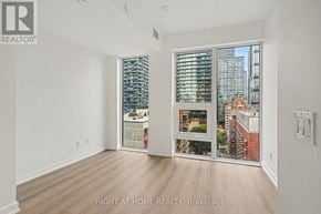 Toronto (Church-Yonge Corridor) condo for rent - A room with a large window showing a cityscape and a picture of a house on the window sill.