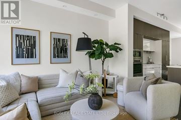 Toronto (Kensington-Chinatown) townhouse for rent - A living room with a grey couch, a coffee table with a plant and a lamp on it, and two framed pictures on the wall.
