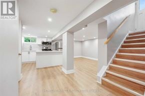 Oshawa (O'neill) apartment for rent - A spacious, well-lit room with wooden floors and a staircase leading to another level.