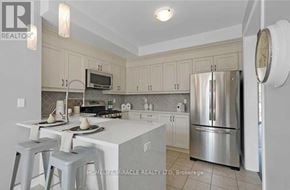 Clarington (Newcastle) apartment for rent - A kitchen with white cabinets and a stainless steel refrigerator.