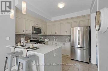 Clarington (Newcastle) apartment for rent - A kitchen with white cabinets and a stainless steel refrigerator.