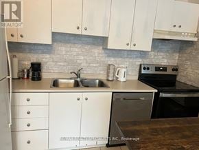 Toronto (Niagara) condo for rent - A kitchen with white cabinets and a stone backsplash.