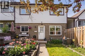 Kitchener townhouse for rent - A house with a white door and windows, a small garden with flowers, and a wooden fence.