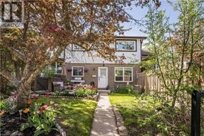 Kitchener townhouse for rent - A house with a white door and windows is surrounded by a garden with a variety of plants and flowers.