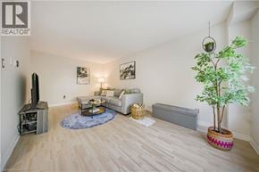 Kitchener townhouse for rent - A living room with a white couch, a coffee table, a plant, and pictures on the wall.