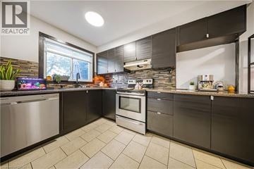 Kitchener townhouse for rent - A modern kitchen with a stainless steel refrigerator and a stone backsplash.