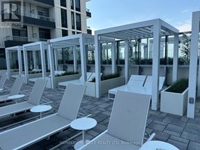 Vaughan (Vaughan Corporate Centre) condo for rent - A row of white lounge chairs and tables are set up on a rooftop.