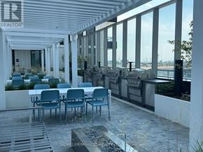 Vaughan (Vaughan Corporate Centre) condo for rent - A patio with a table and chairs overlooking a body of water.