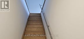 St. Catharines (Oakdale) townhouse for rent - A staircase with a wooden handrail leads up to a white wall.