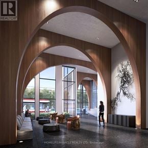 Toronto (South Parkdale) condo for rent - A woman is walking through a large, open-concept lobby with wooden archways and a large sculpture on the wall.